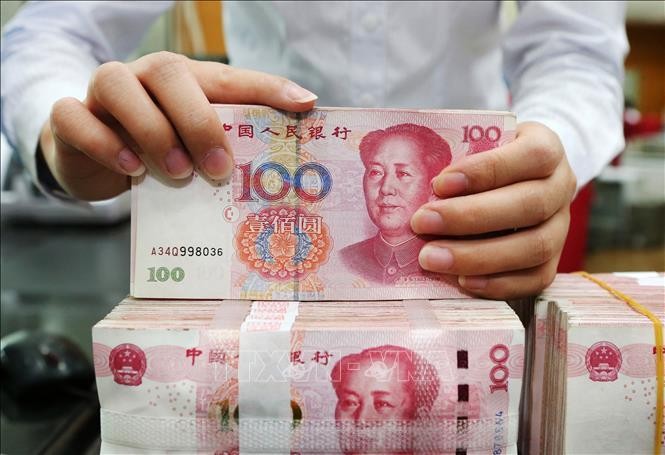 Nhân viên ngân hàng kiểm tiền mệnh giá 100 nhân dân tệ tại tỉnh Giang Tô, Trung Quốc. Ảnh: AFP/TTXVN